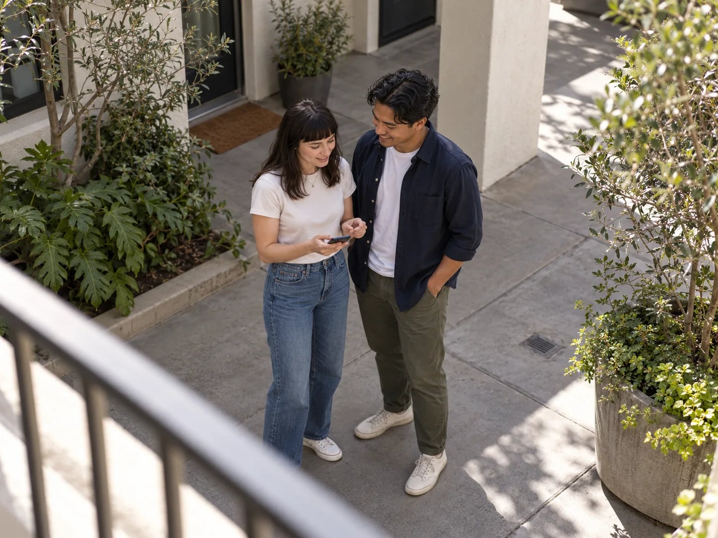 A couple in a sunny courtyard, looking at a phone together