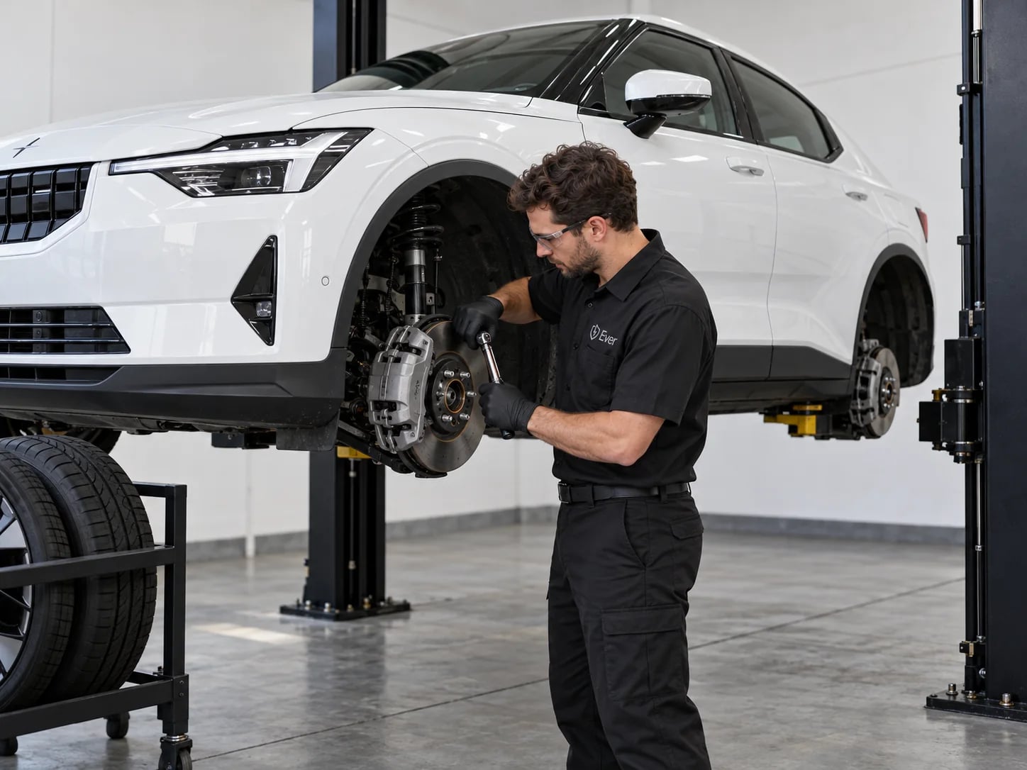 An Ever technician torquing a brake caliper on a white EV raised on a lift