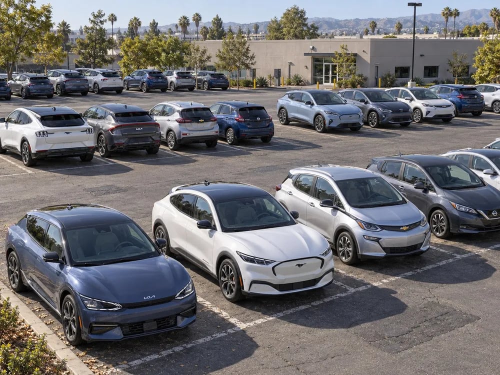 Rows of electric cars and crossovers parked across a sunny fleet lot